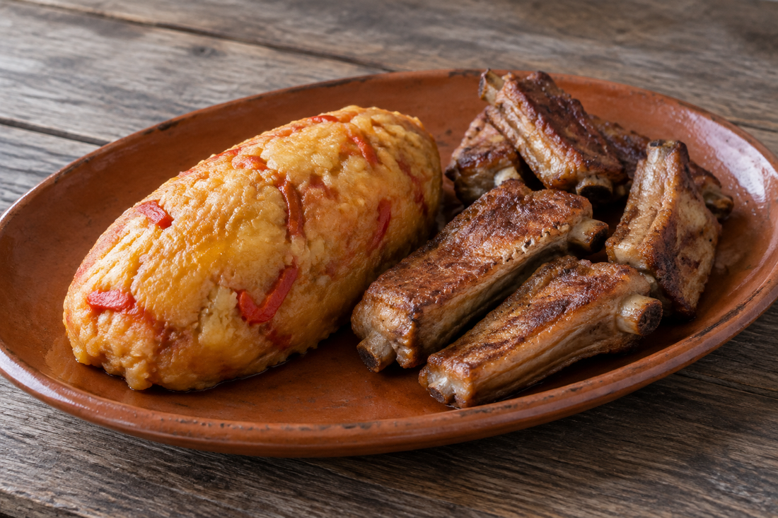 Migas de batata com pão, tomate e pimento moldadas em rolo, servidas com entrecosto frito num prato de barro